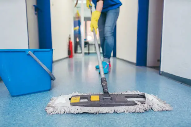Professional cleaner disinfecting shared office touchpoints with organized cleaning equipment